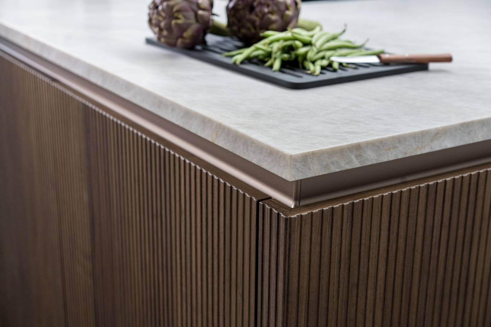 Cuisine haut de gamme en noyer, au design minimal et sans poignées, offrant des lignes épurées, des matériaux nobles et une ambiance moderne et élégante