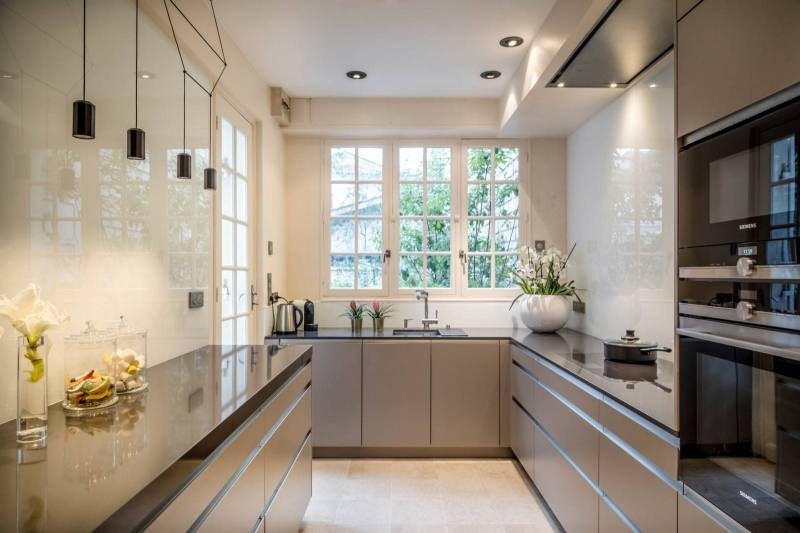 Cuisine moderne et épurée avec éclairage suspendu, matériaux haut de gamme, électroménagers intégrés et foyer design pour une ambiance chaleureuse