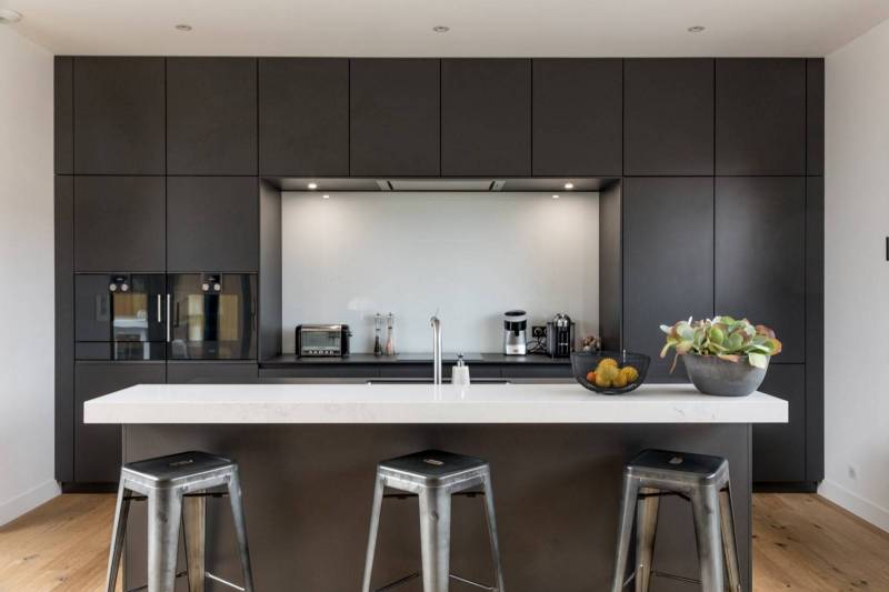 Espace de vie moderne au design épuré, mêlant cuisine noire ouverte, rangements intégrés et matériaux élégants pour une ambiance contemporaine et harmonieuse
